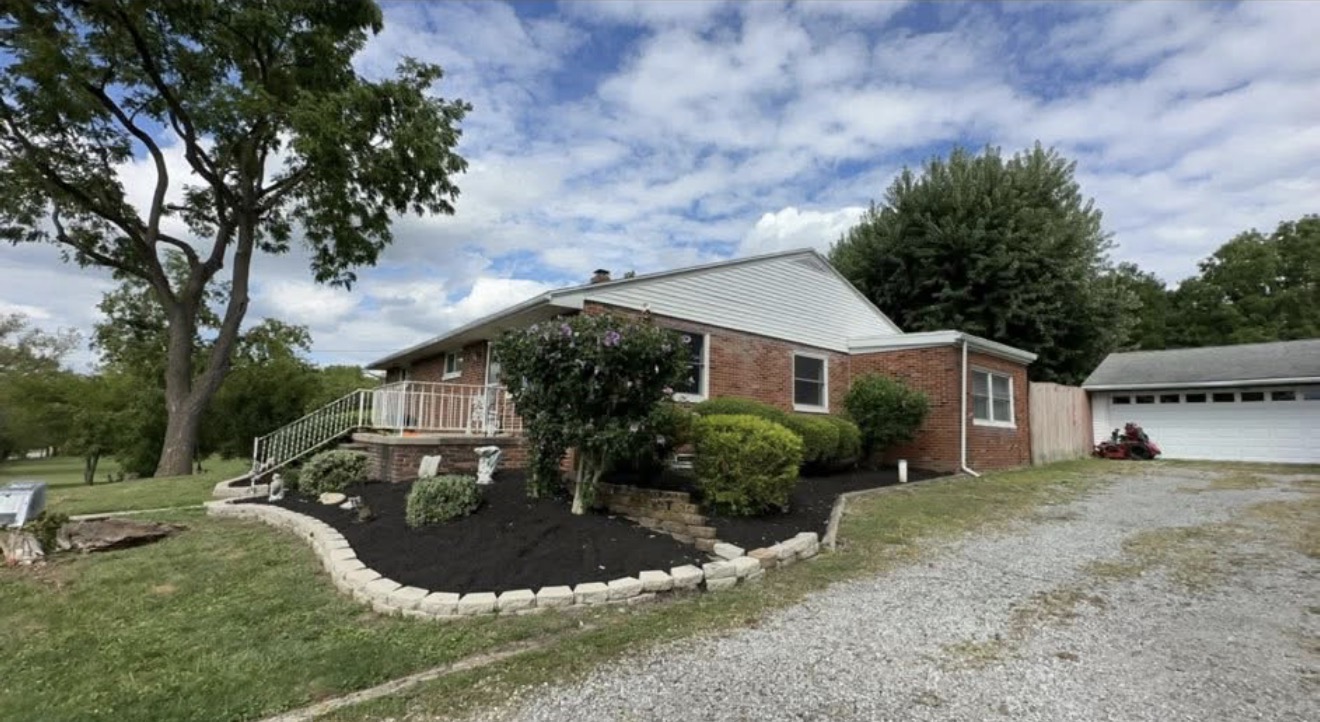 Brick ranch home with new stone-edged mulch bed and trimmed shrubs