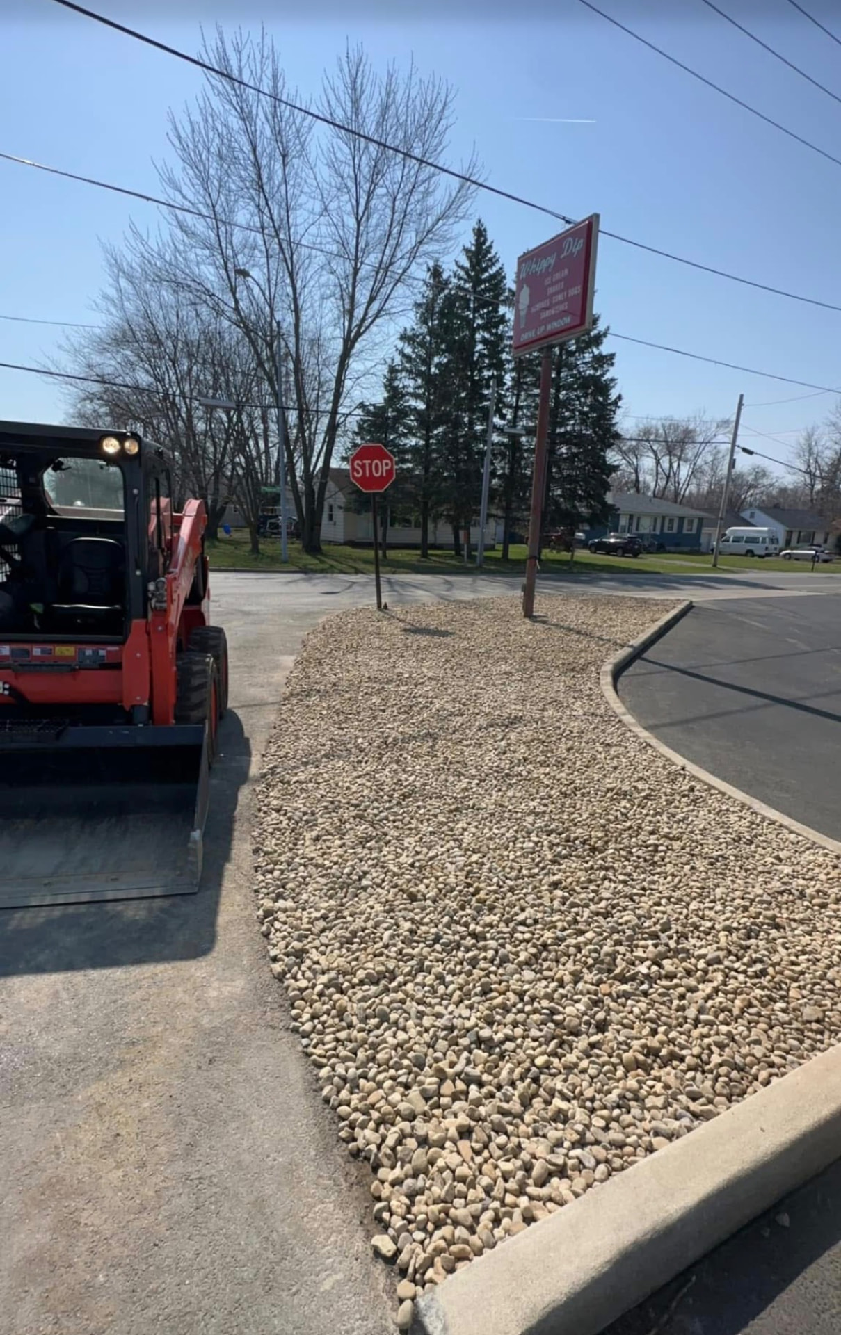 Finished gravel island with new concrete curb and skid steer on site