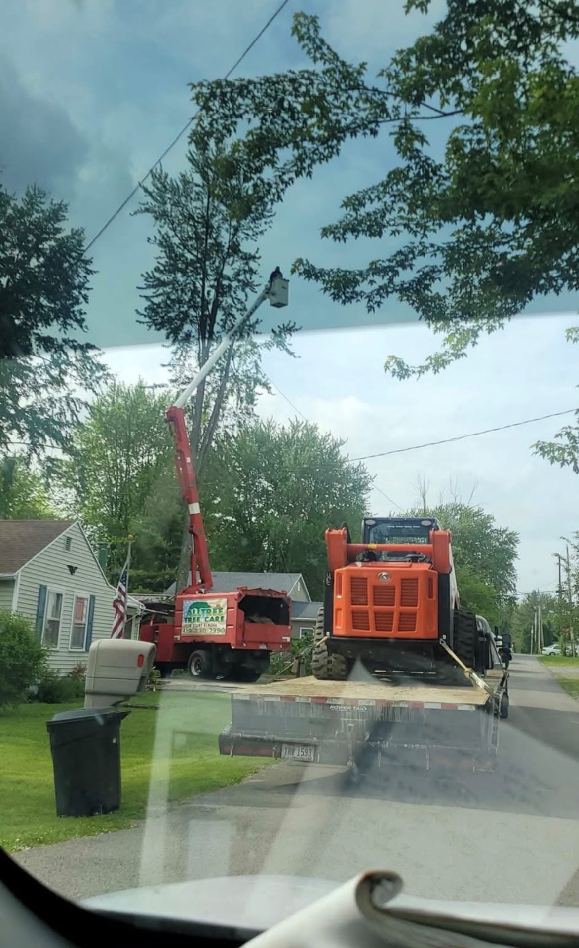 Bucket truck and skid steer on a residential tree removal job